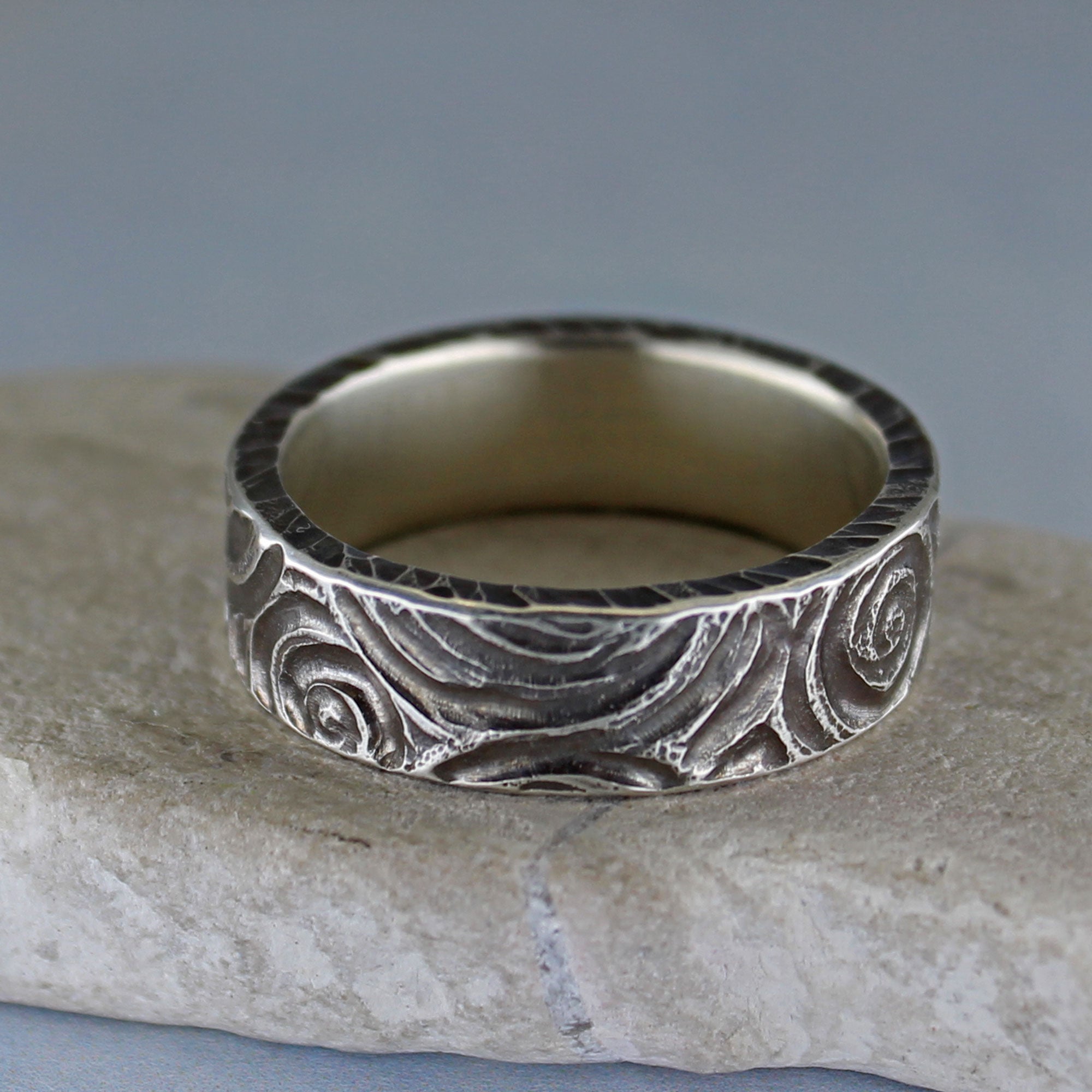 Close-up of hand carved spiral texture on oxidized sterling silver ring