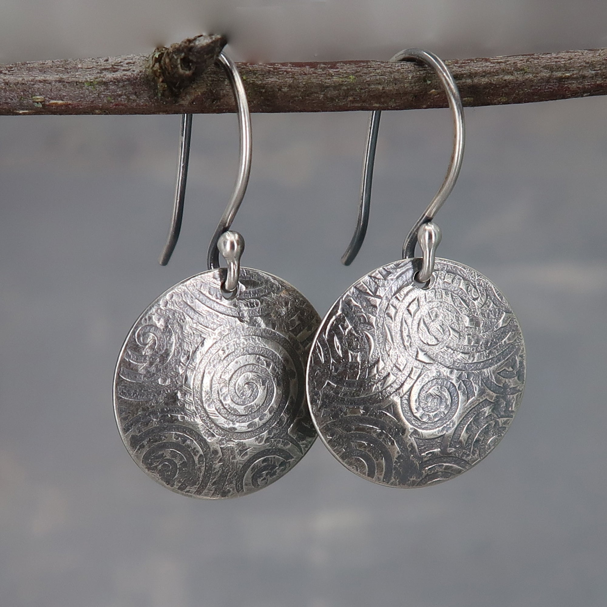 Sterling silver earrings shaped like round shields with spiral pattern