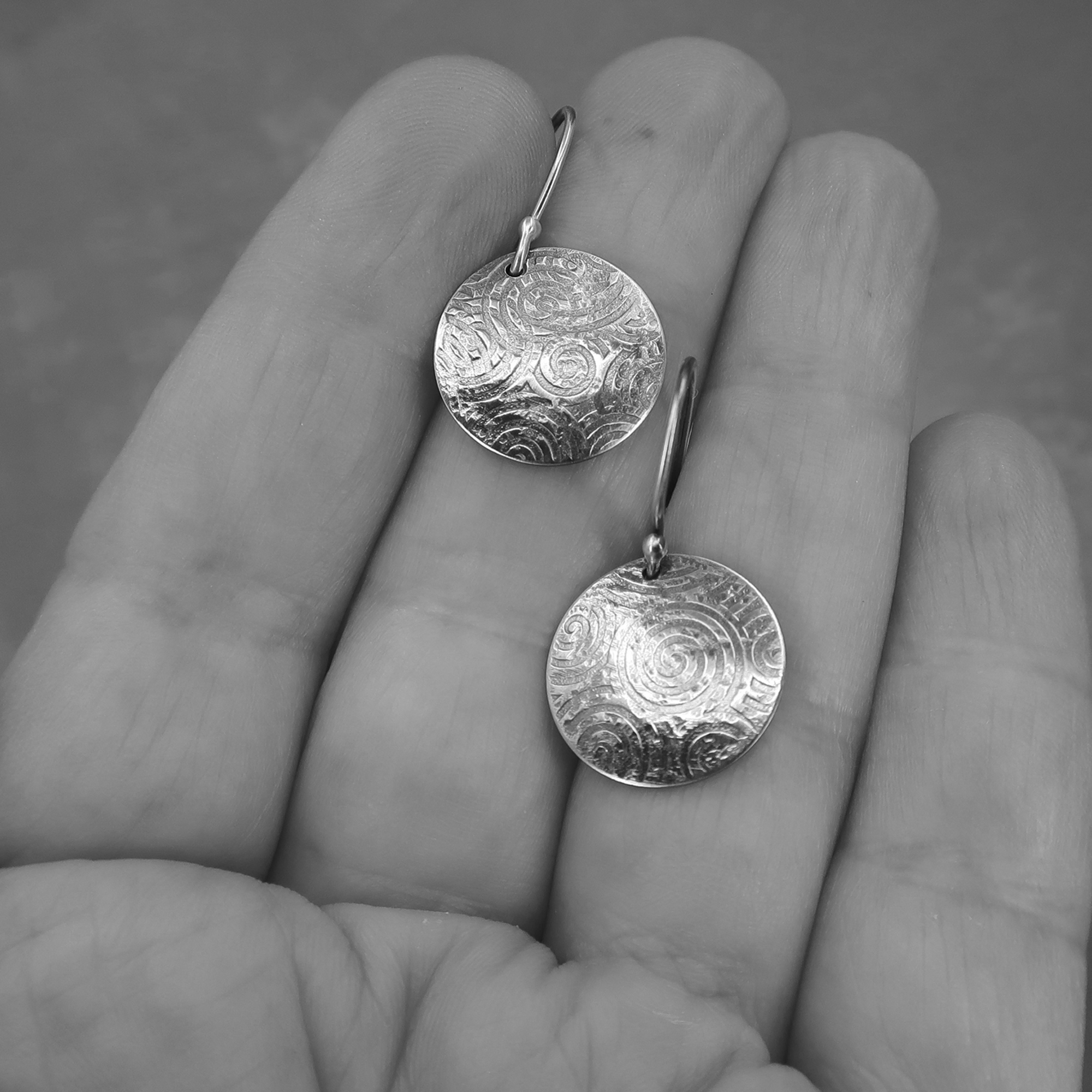 Artisan made sterling silver earrings shown on hand for scale