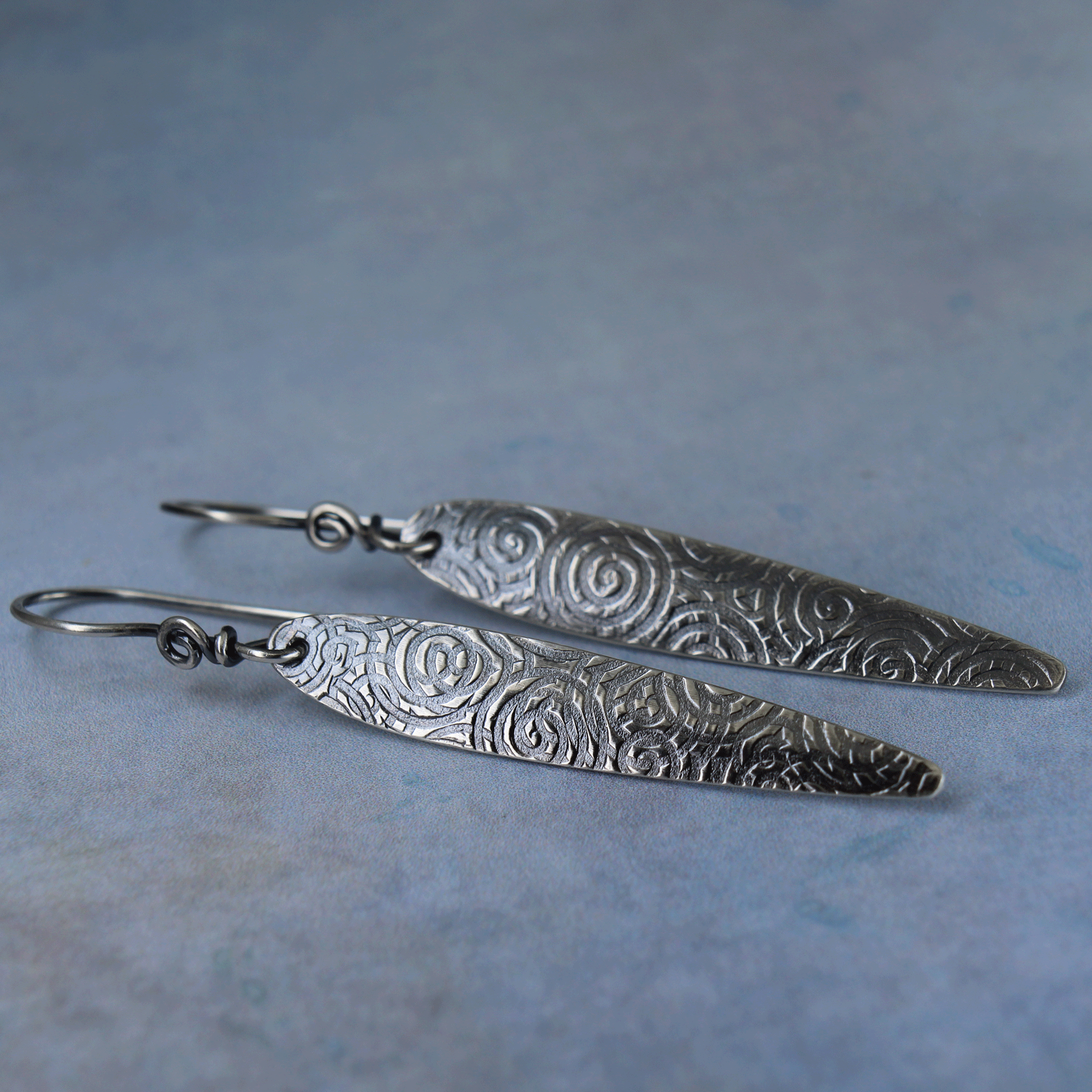 Spear shaped silver earrings with spiral pattern