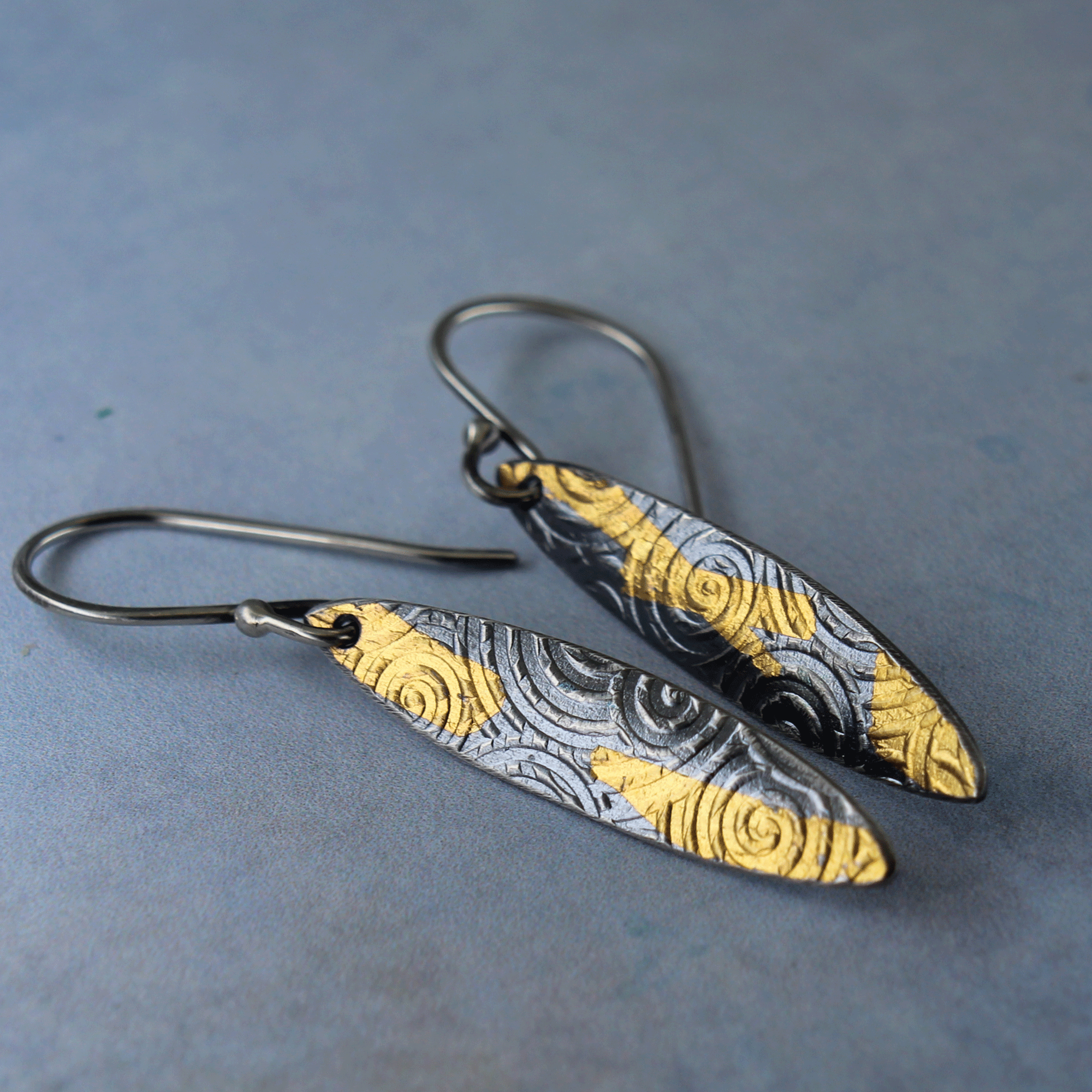 Artisan earrings with shield form and symbolic spiral design