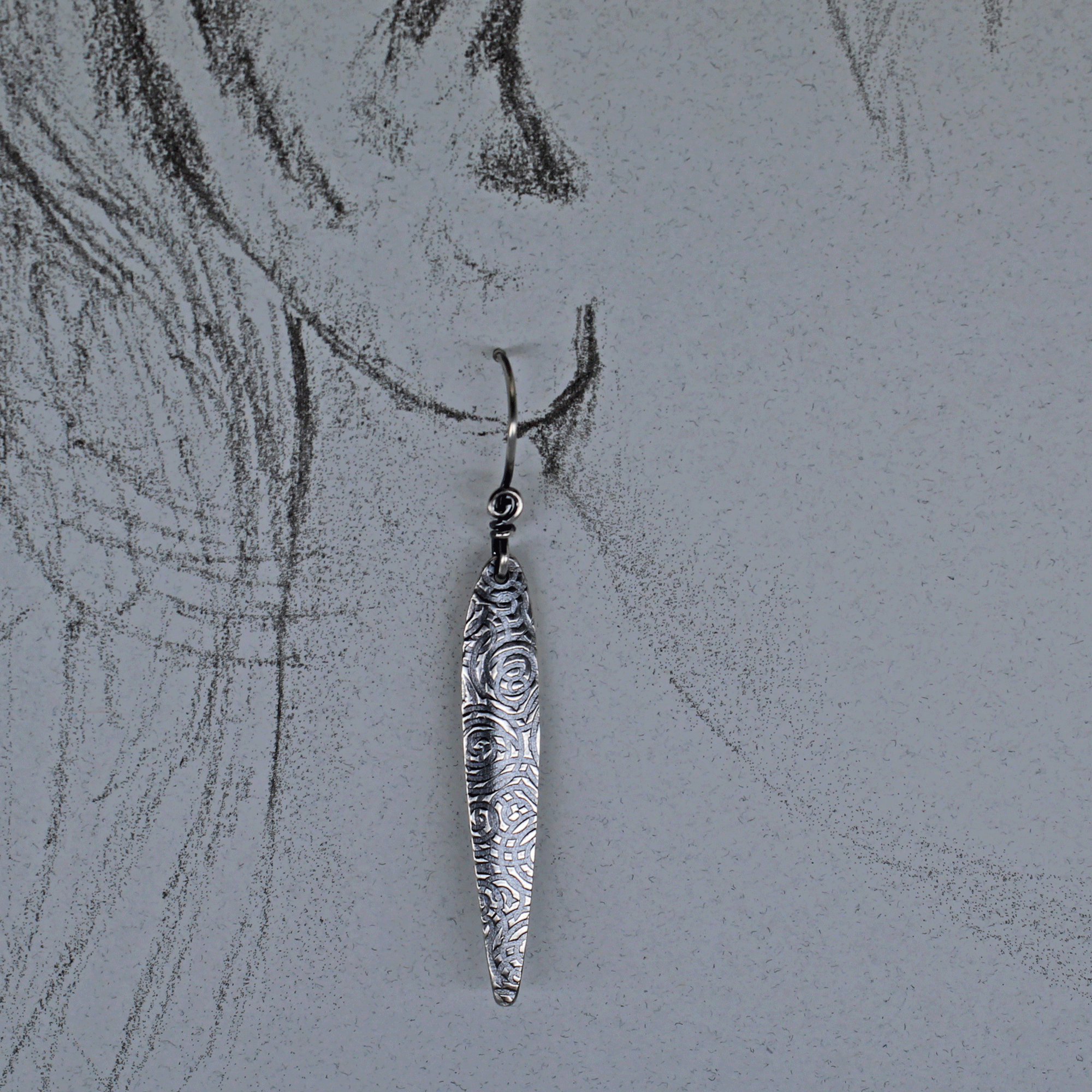 Spear dangle earring shown on life size ear drawing