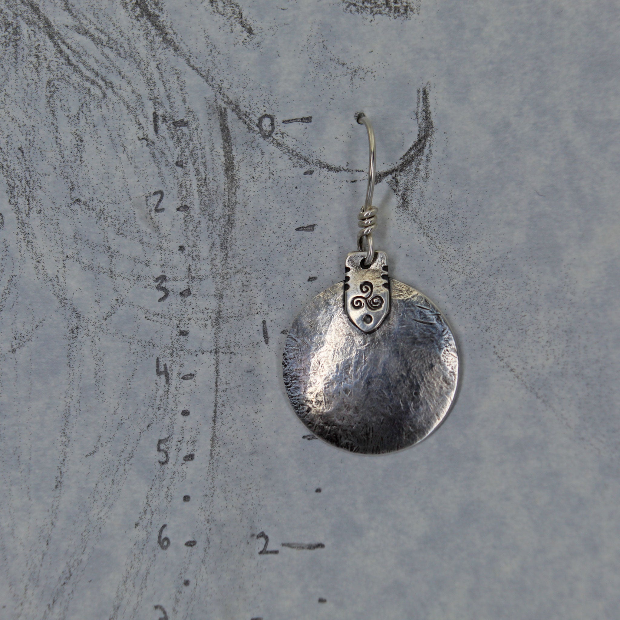Lightly rustic silver discs with triskele symbol shown with measurements