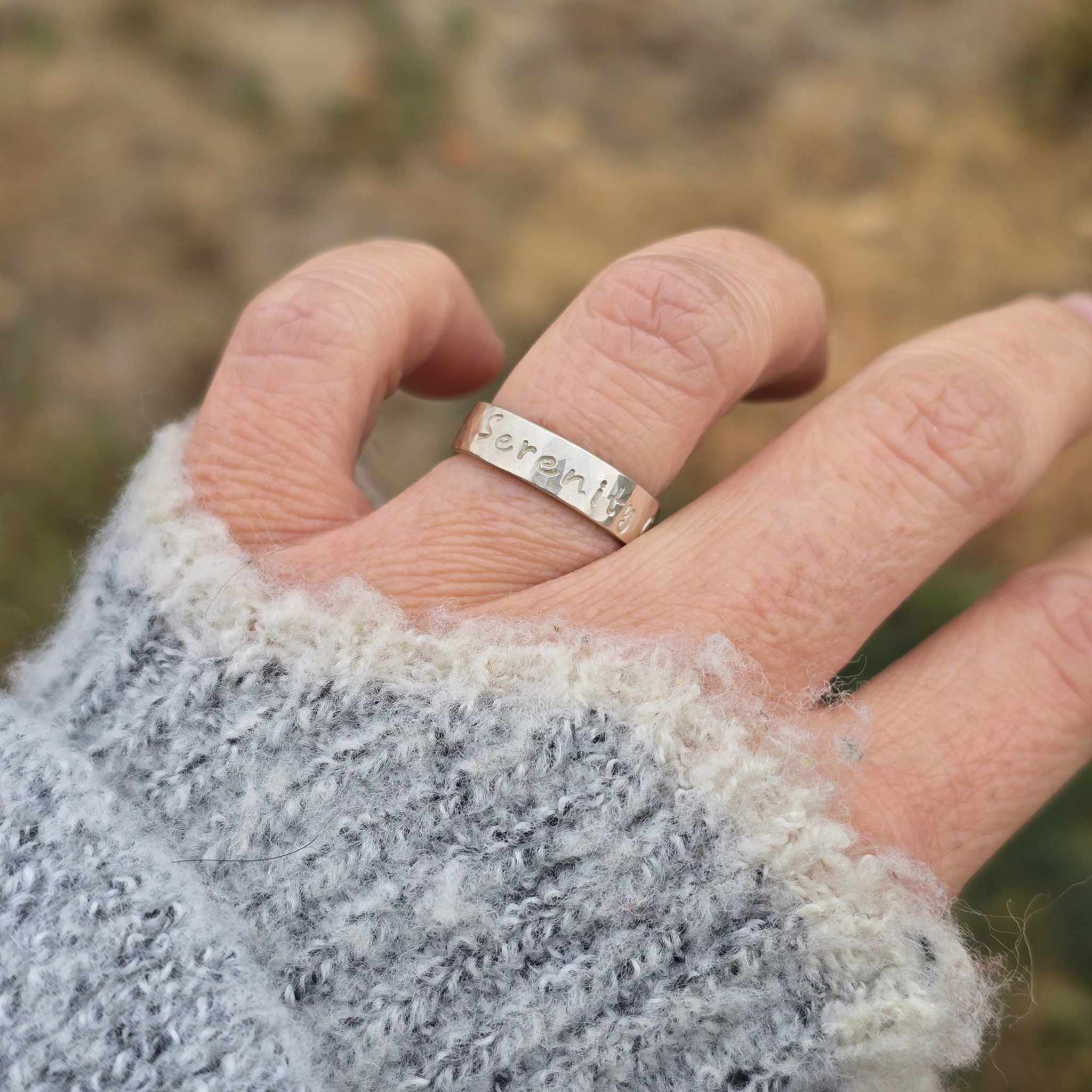 Hand wearing handcrafted silver word ring with gentle hammered finish