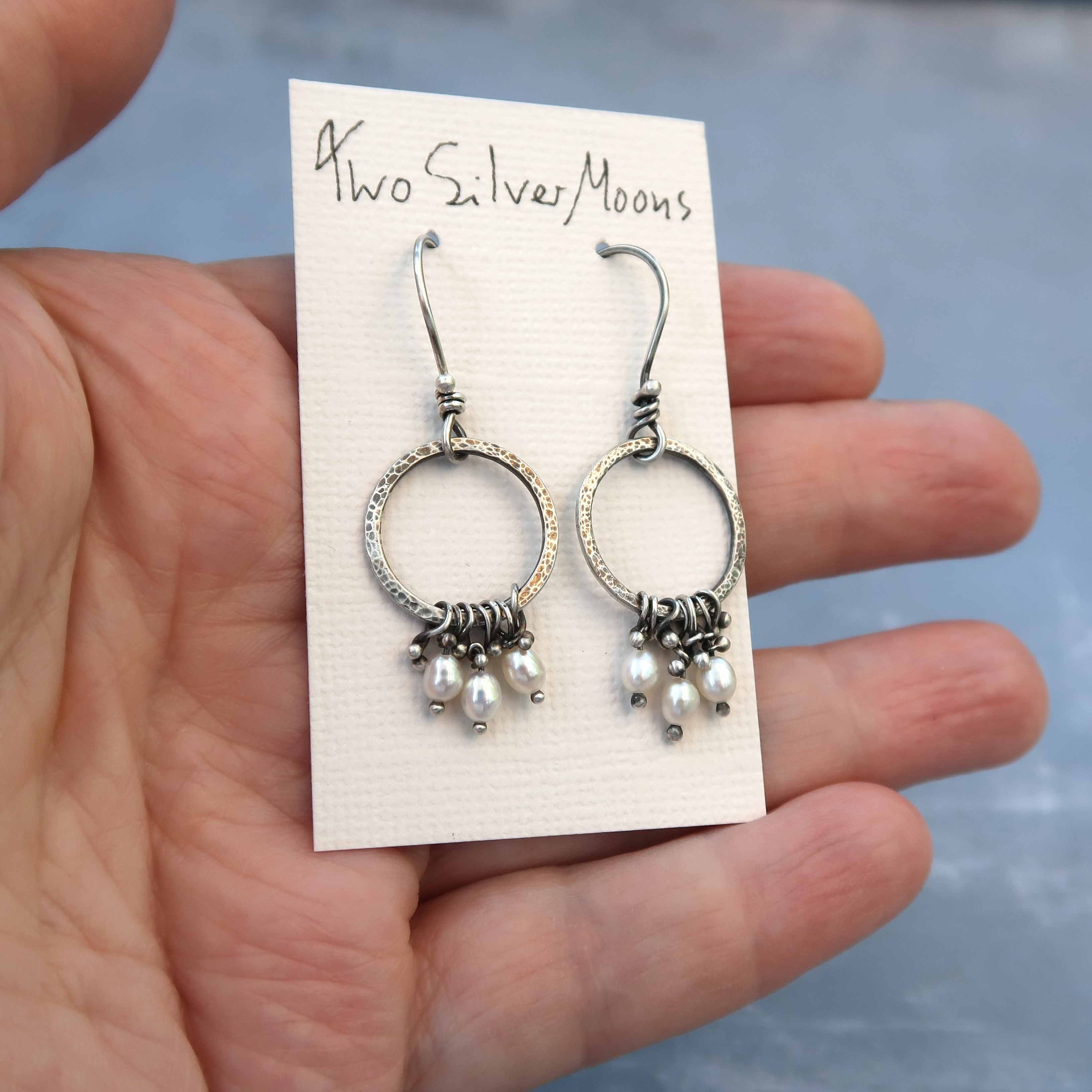 Unique pearl earrings in sterling silver shown on makers hand for scale