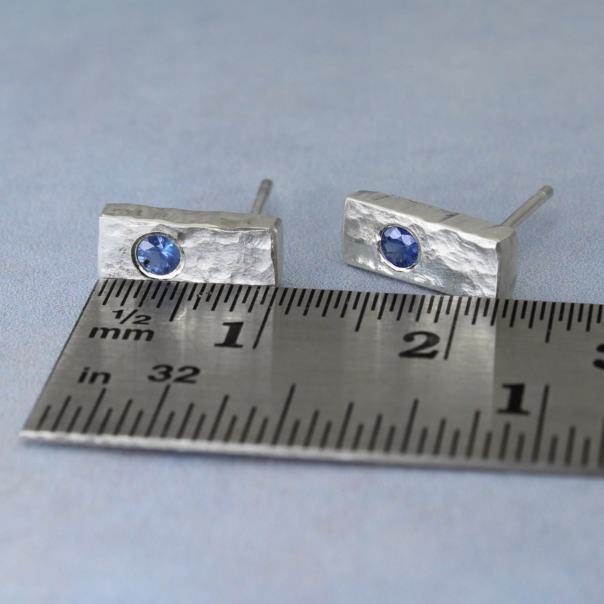 Stud earrings handmade in silver, shown on ruler for size