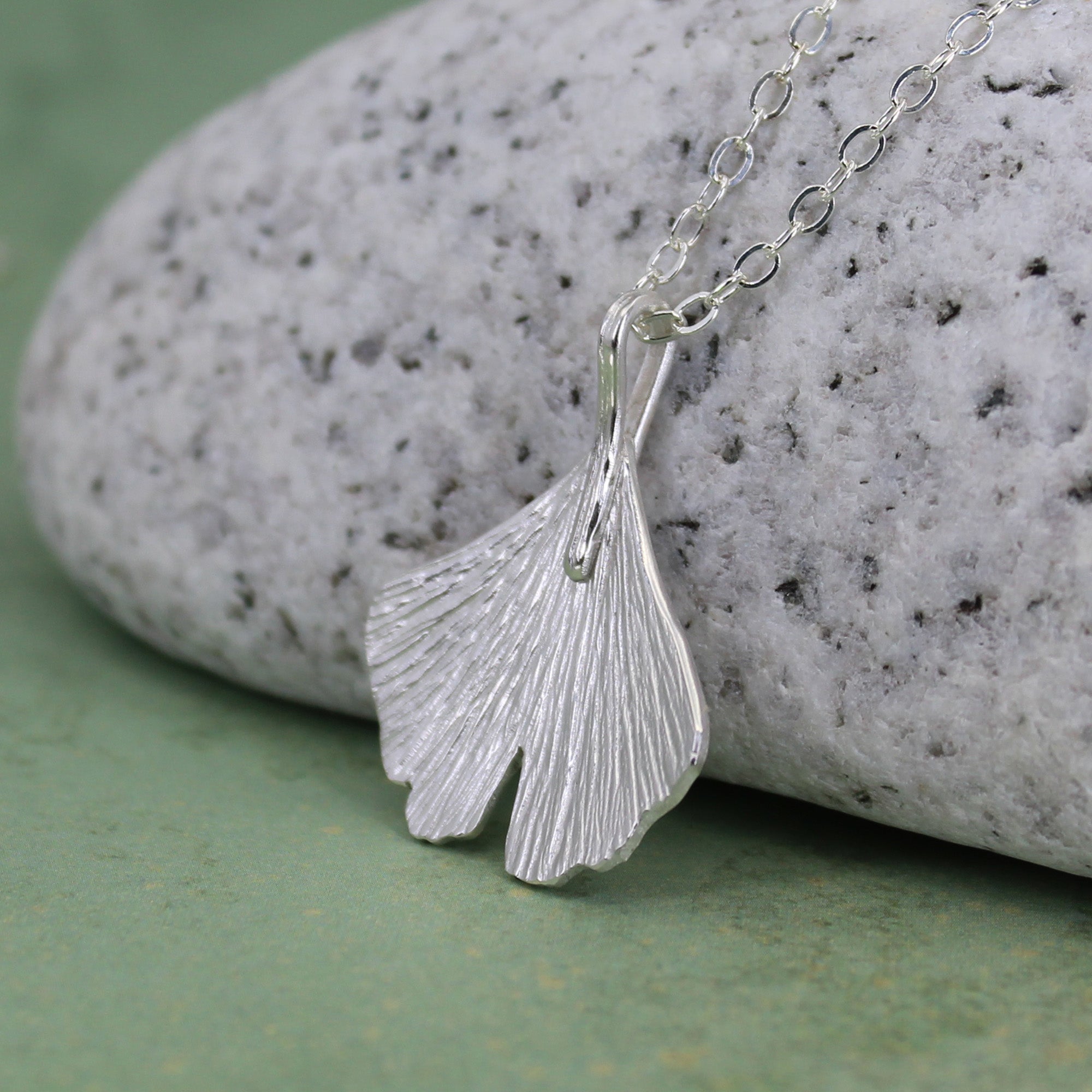 Close-up of hand-cut ginkgo leaf pendant with engraved detail