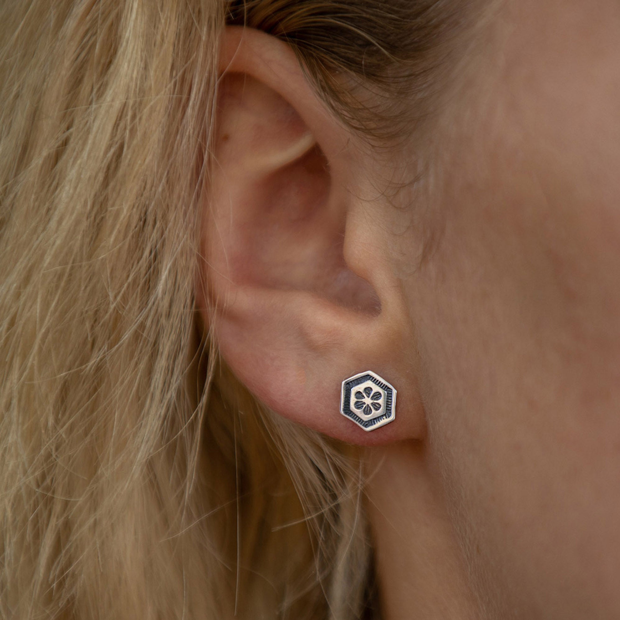 Floral silver hexagon stud earrings worn by model
