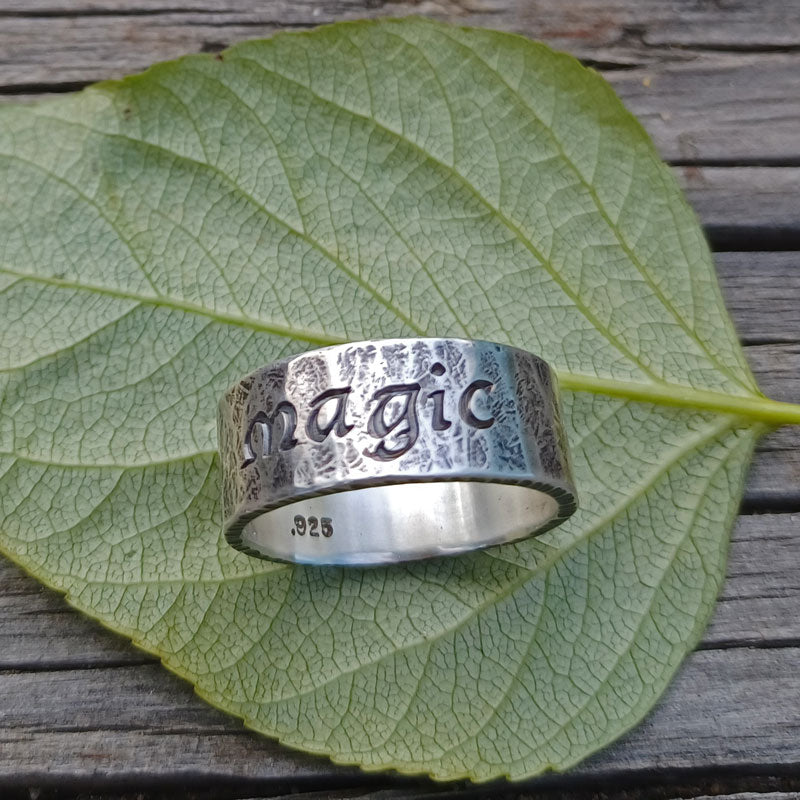 Silver ring with 'magic' engraving on a green leaf
