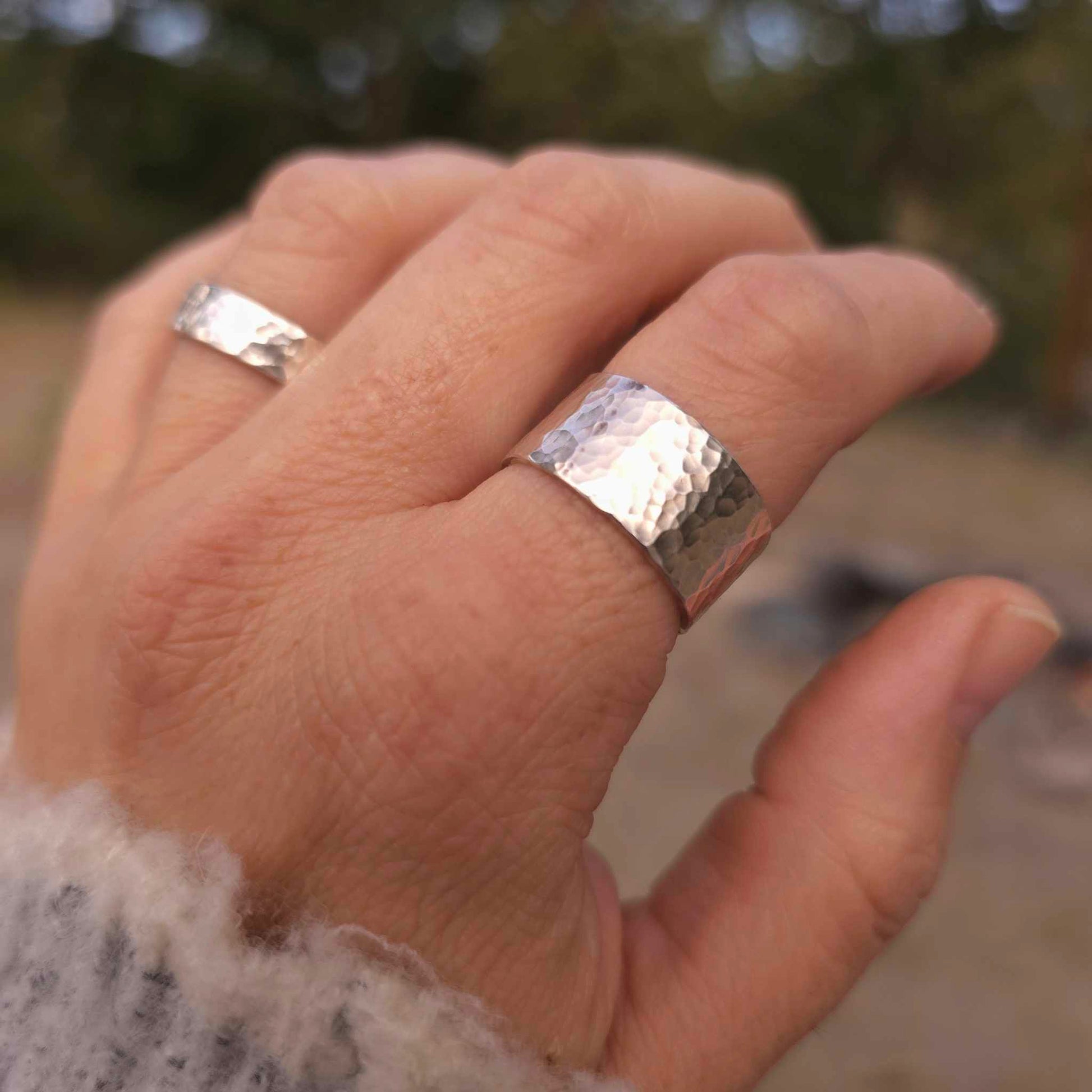 Wide hammered silver ring shown on hand