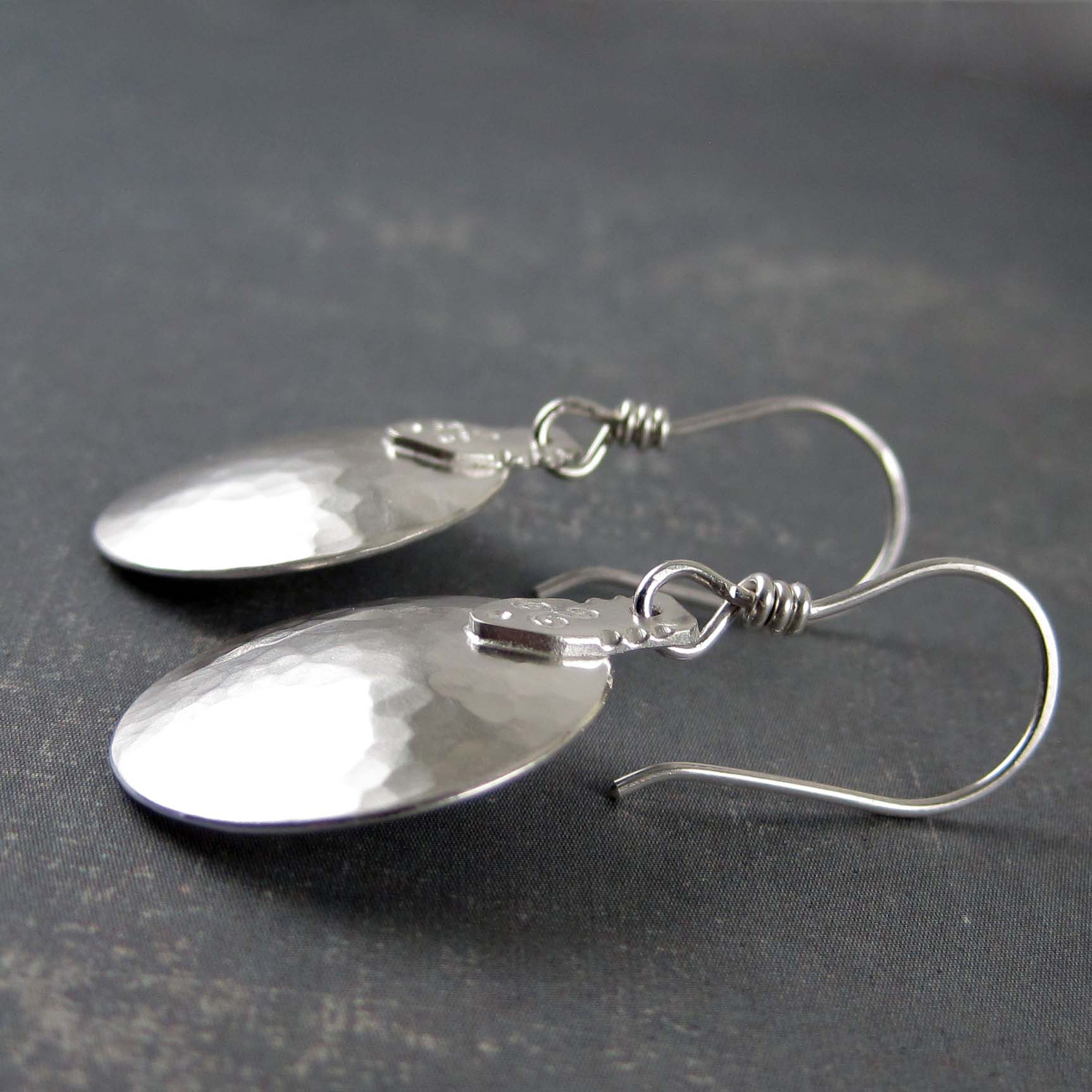 Sideview of slightly domed silver discs with a triskele symbol accent