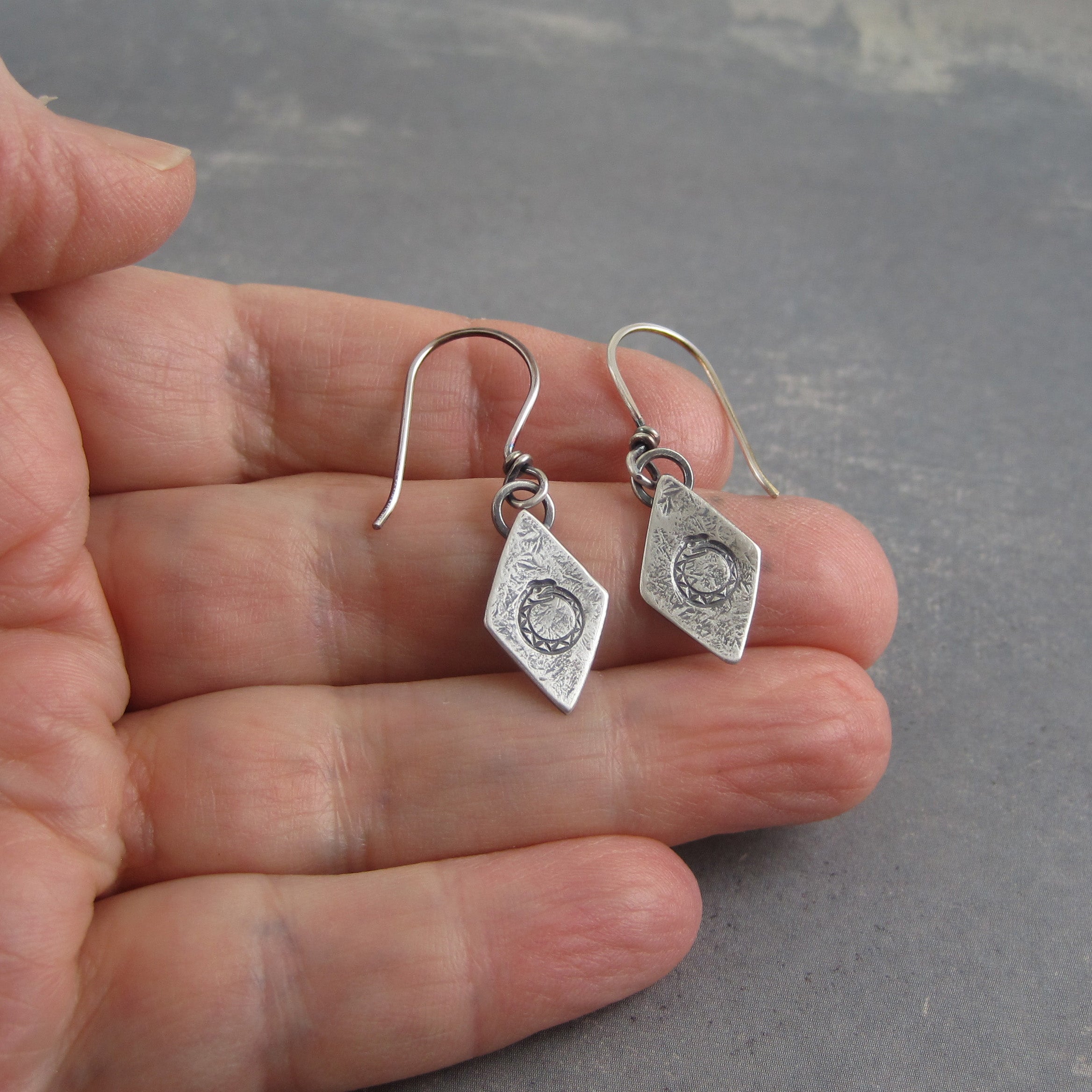 Handmade ouroboros earrings shown on hand for scale