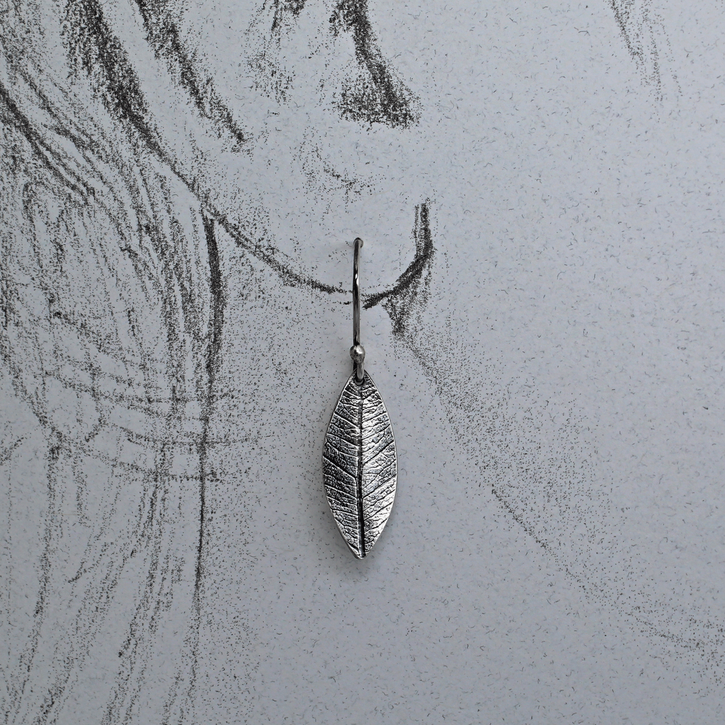 Leaf imprint silver earring shown on life size ear drawing