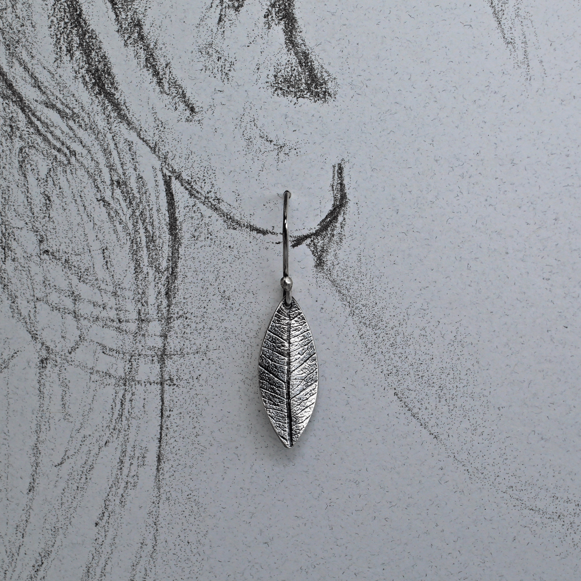 Leaf imprint silver earring shown on life size ear drawing