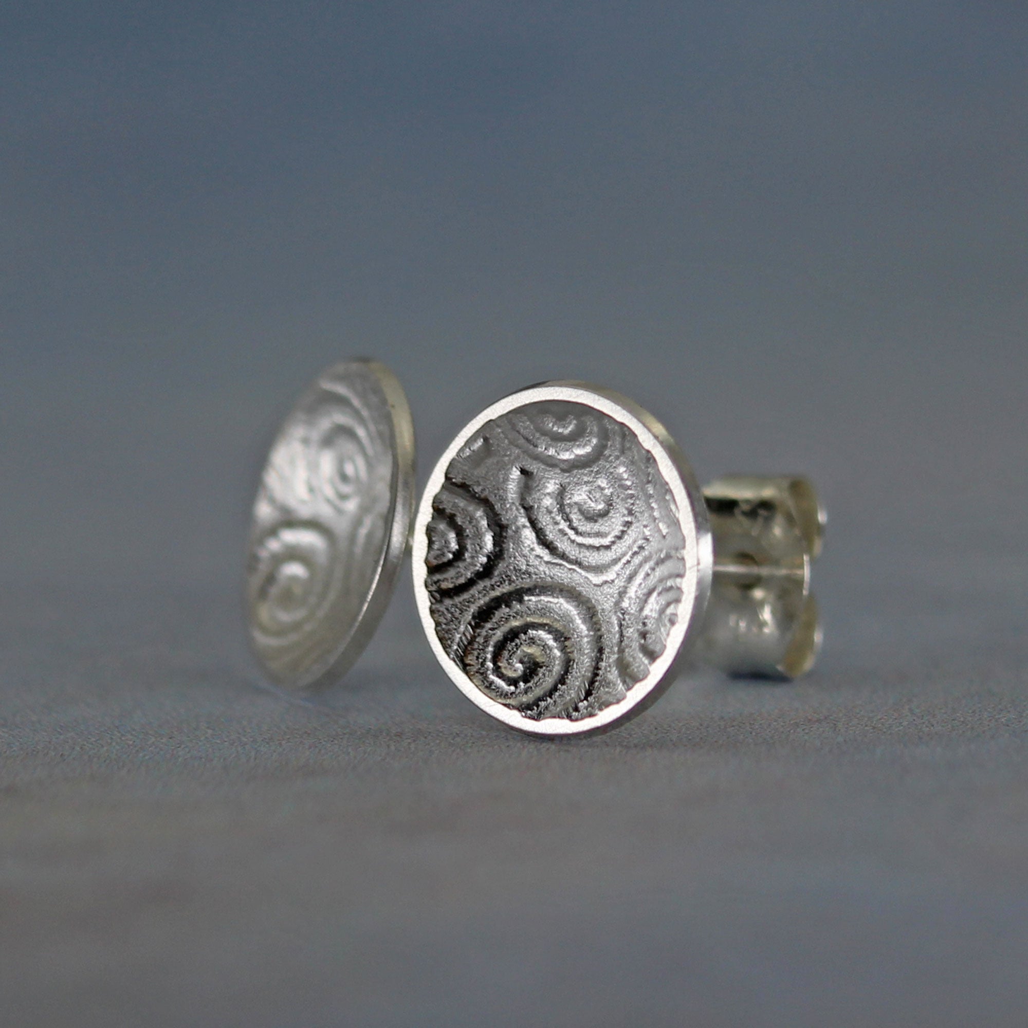 Side view of sterling silver concave disc stud earrings with burnished edges