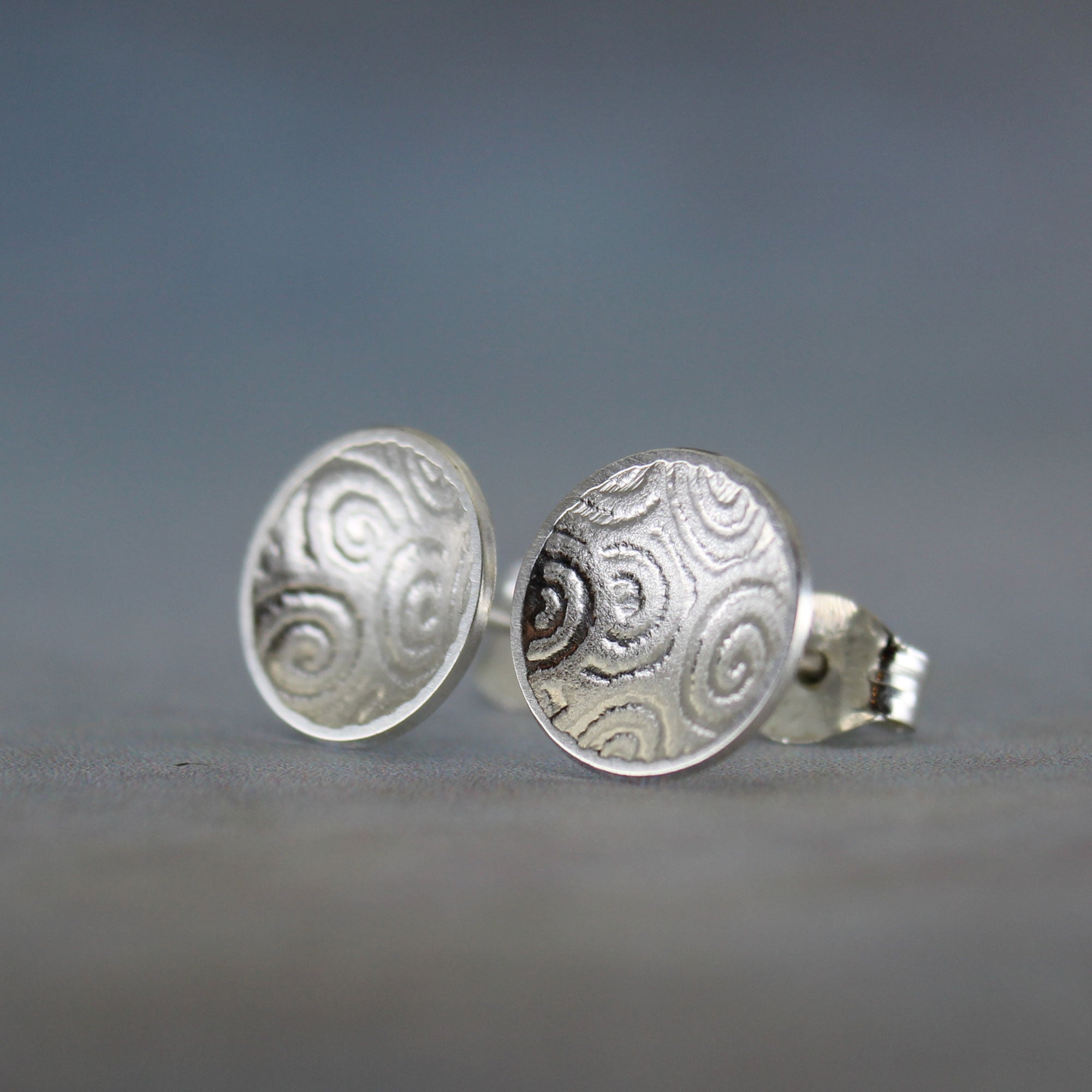 Handmade sterling silver concave disc stud earrings with subtle spiral pattern
