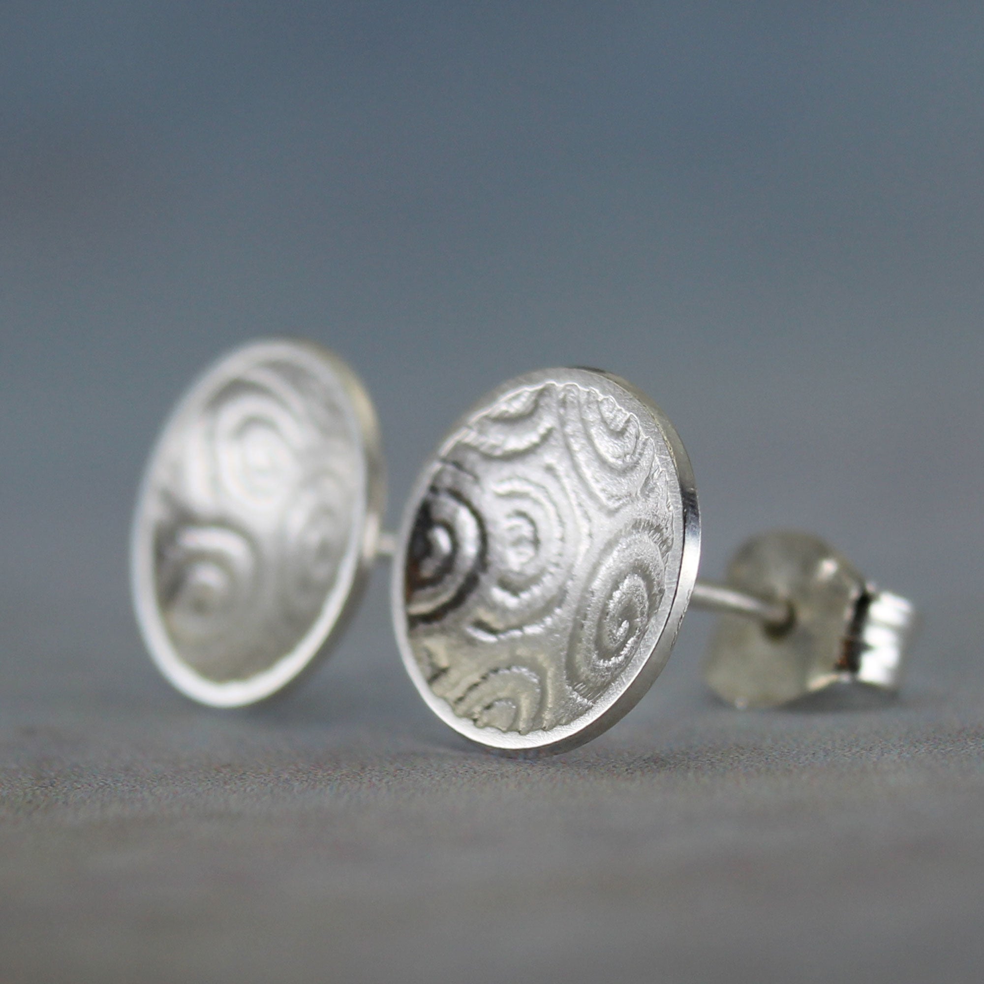 Close-up of embossed spiral design on sterling silver concave disc earrings