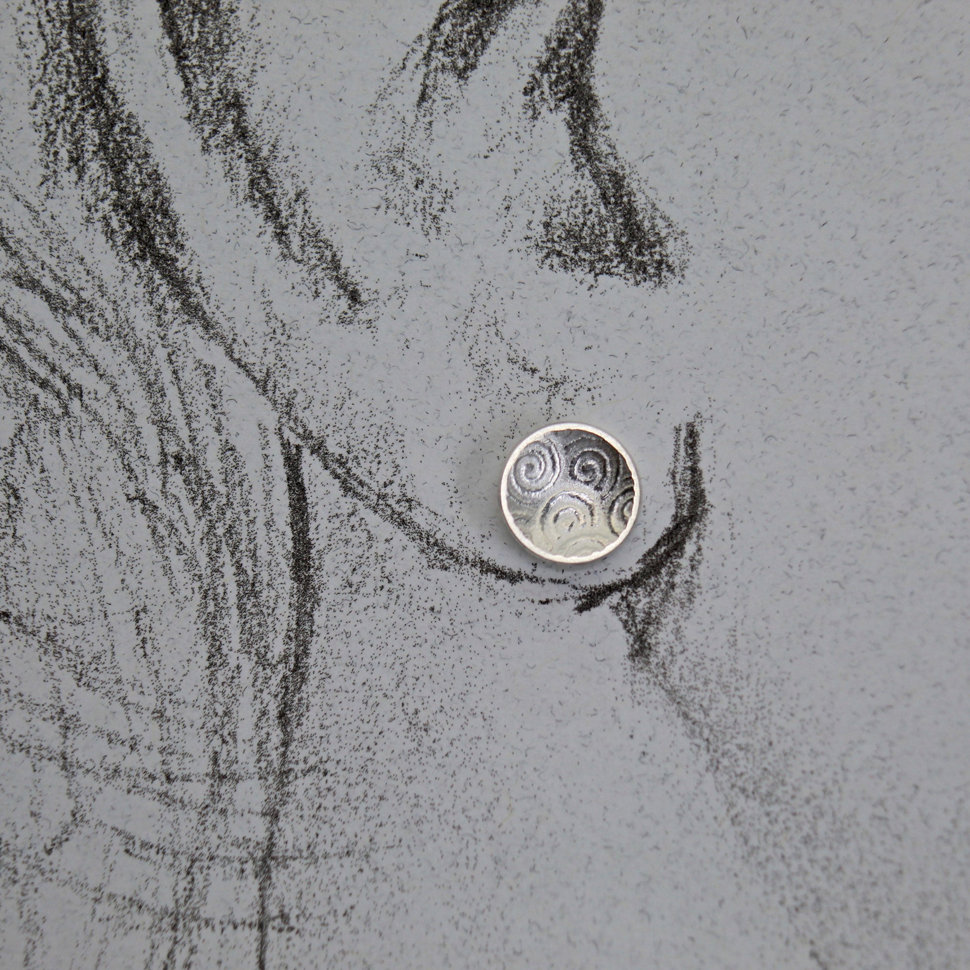 silver stud earrings shown on life-size drawing of an ear