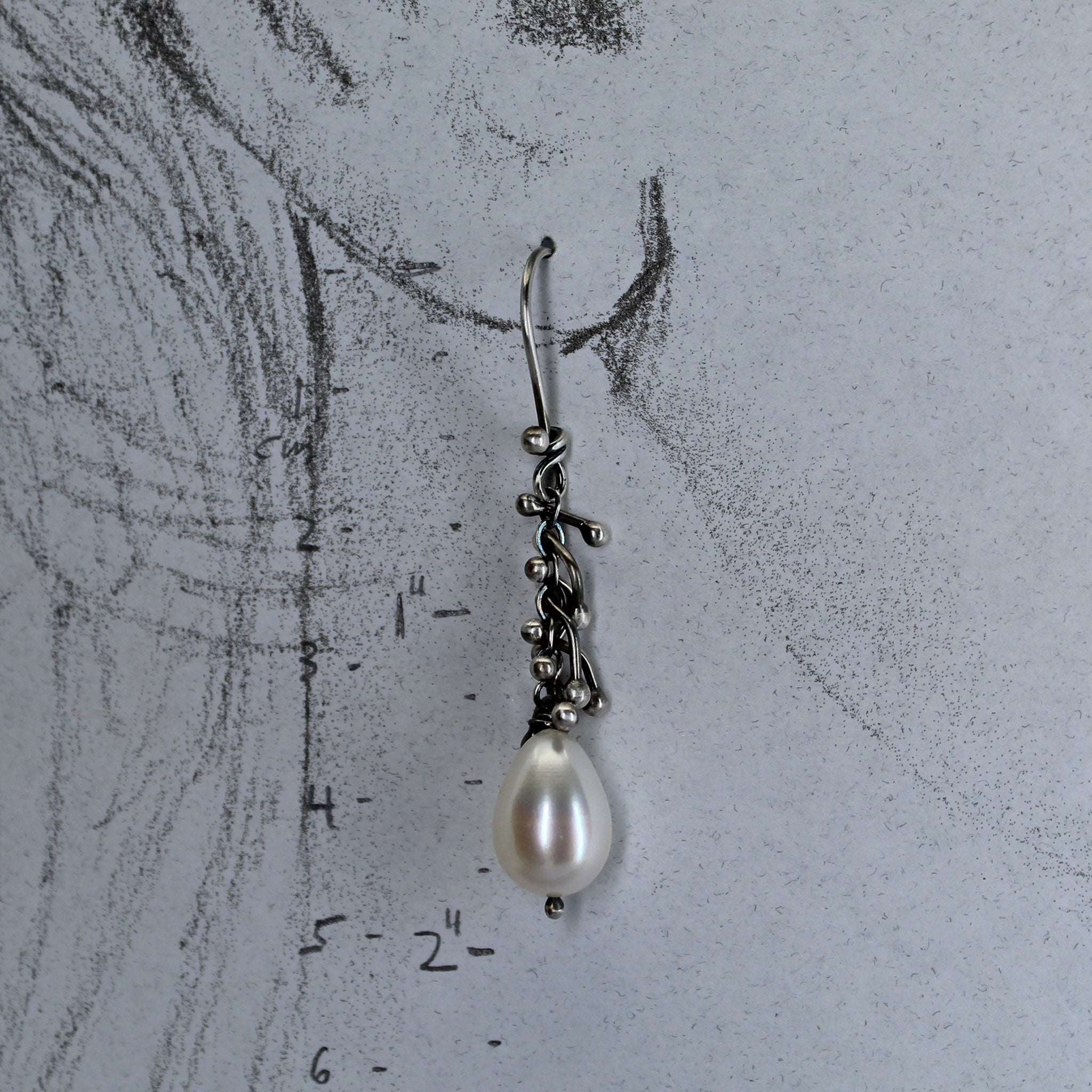 Earrings shown  on a pencil drawing of a life size ear with measurements