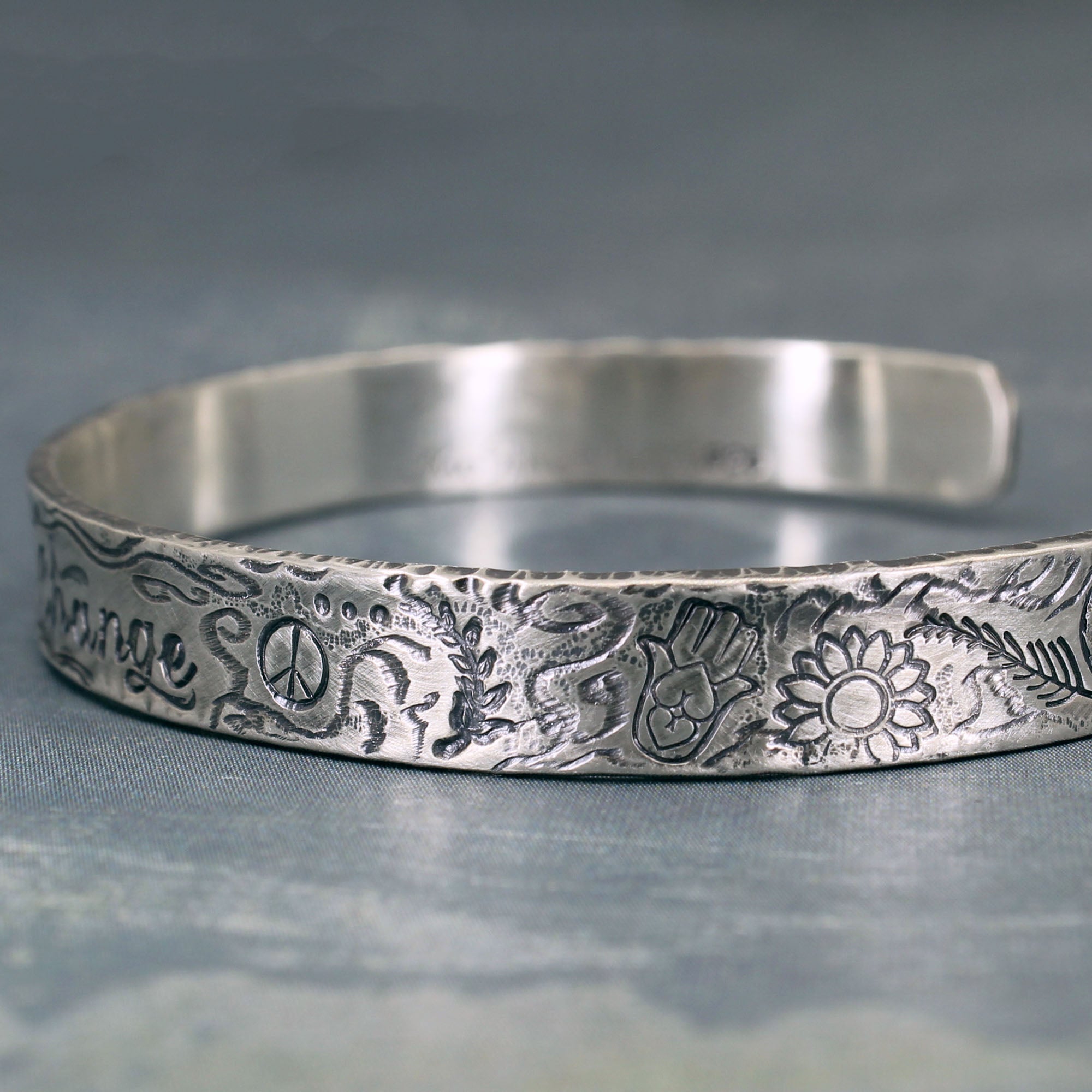 lose-up of handcrafted silver bracelet with aged patina and inspirational symbols 