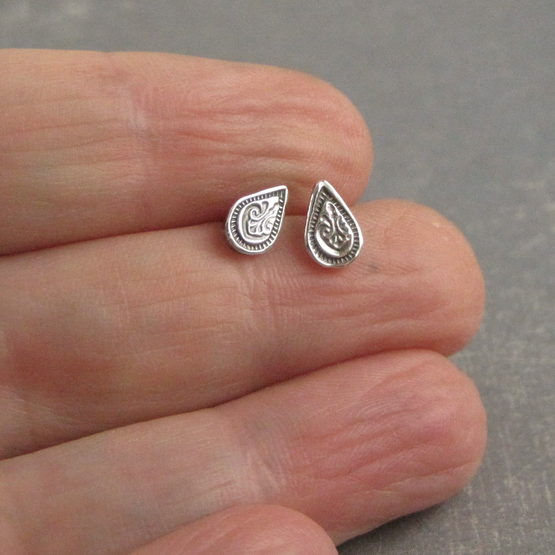 Small teardrop post earrings shown on hand for scale