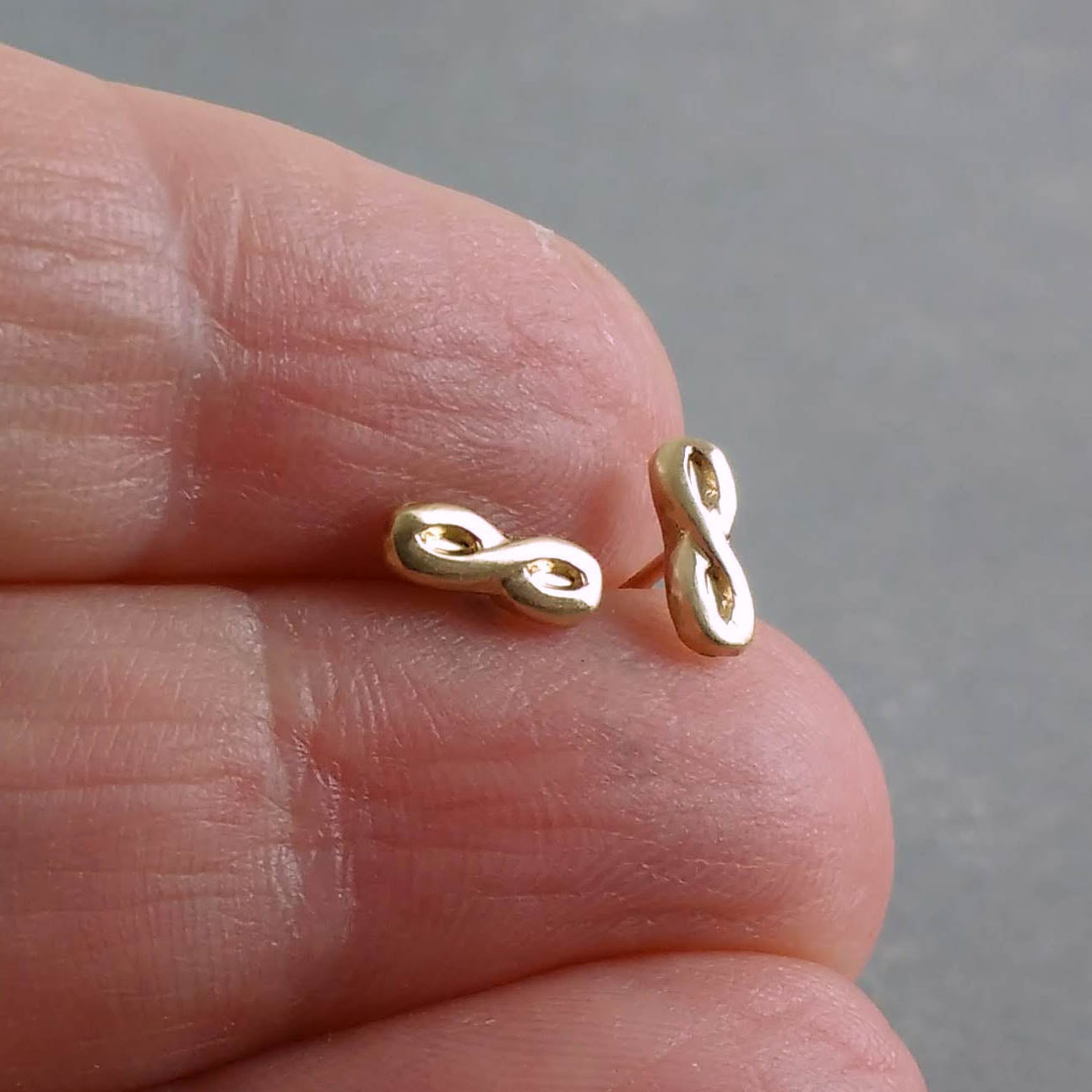 14k infinity post earrings on hand