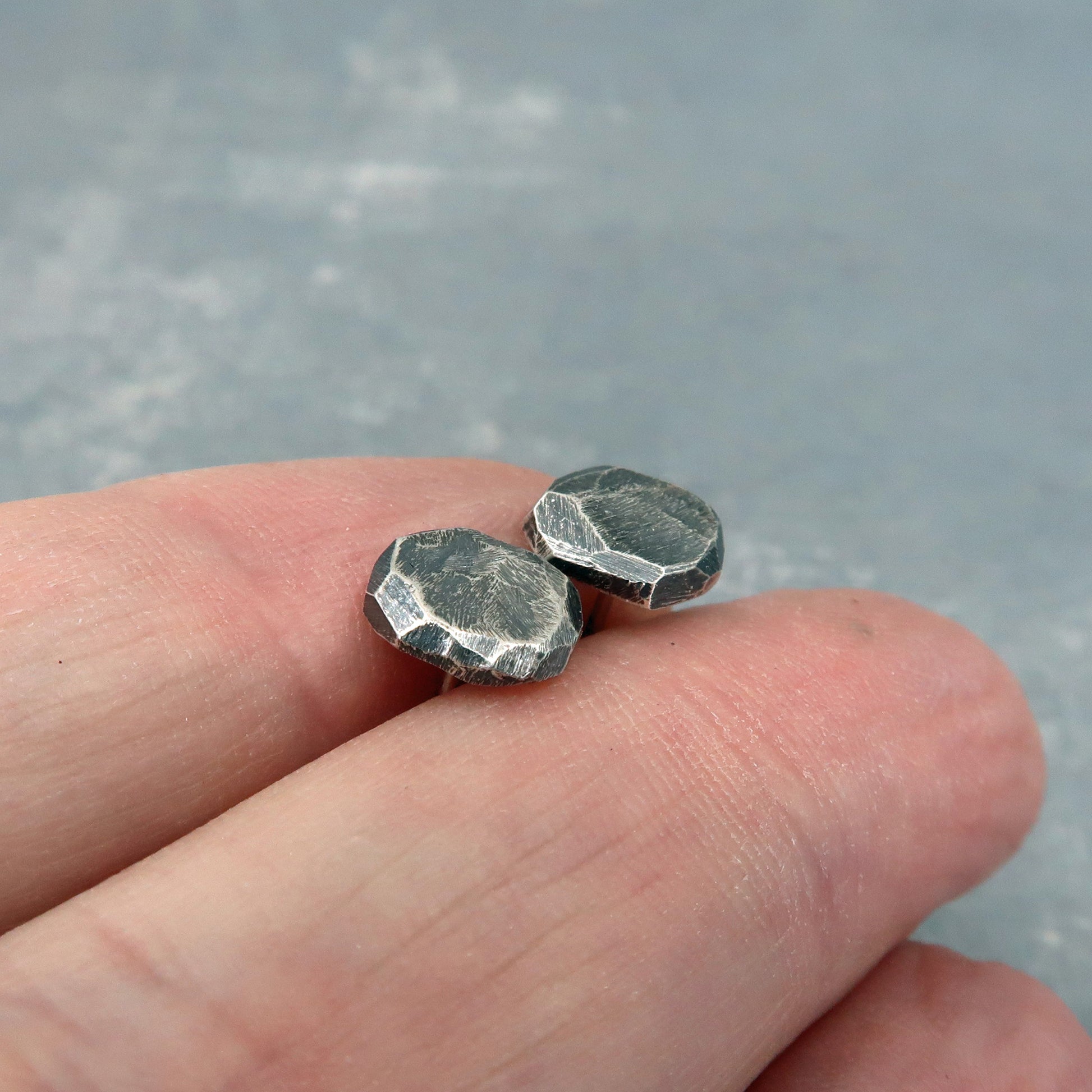 Rustic sterling silver studs shown on hand